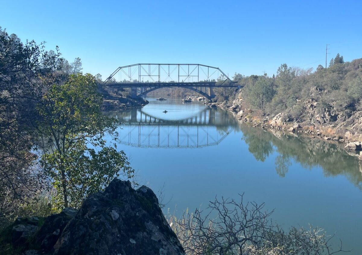Rainbow Bridge spanning a calm waterway with a small paddler below