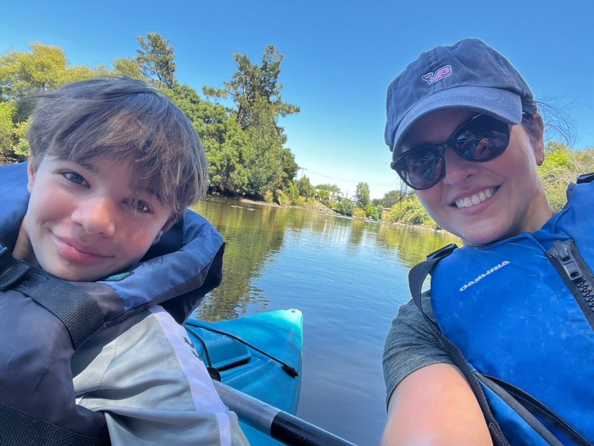 A mother and son wearing life jackets pose for a selfie while kayaking on the Napa River.